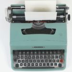 A muted blue manual typewriter on a white background